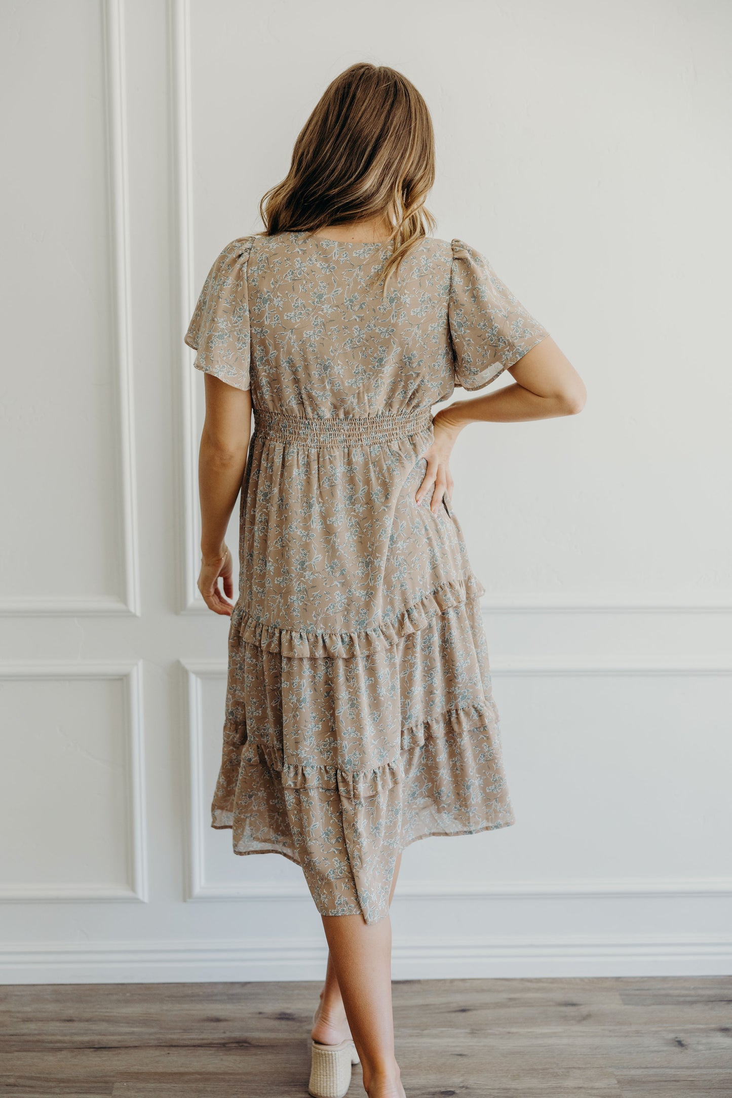 Back of dress with taupe and teal print, and fit and flair silhouette.